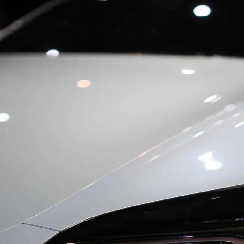Tesla Model 3 引擎蓋貼亮面透明犀牛皮後的反光特寫，原廠白漆光澤保留