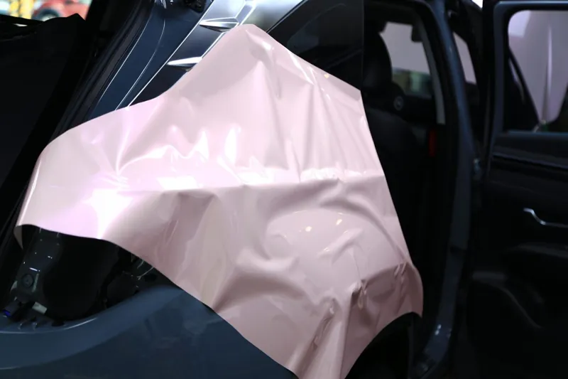 整片粉色改色膜先鬆鬆攤在 Hyundai Tucson 車尾，順著車身弧度找方向